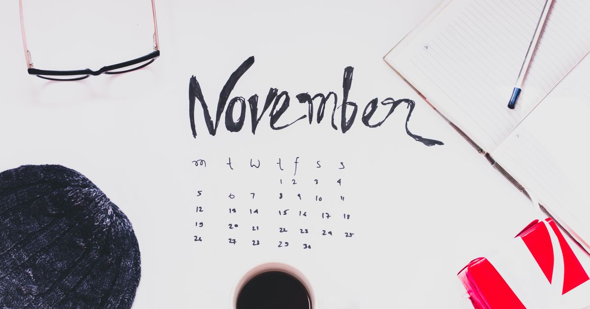 November desk calendar flat lay with coffee, sweater, and notebook