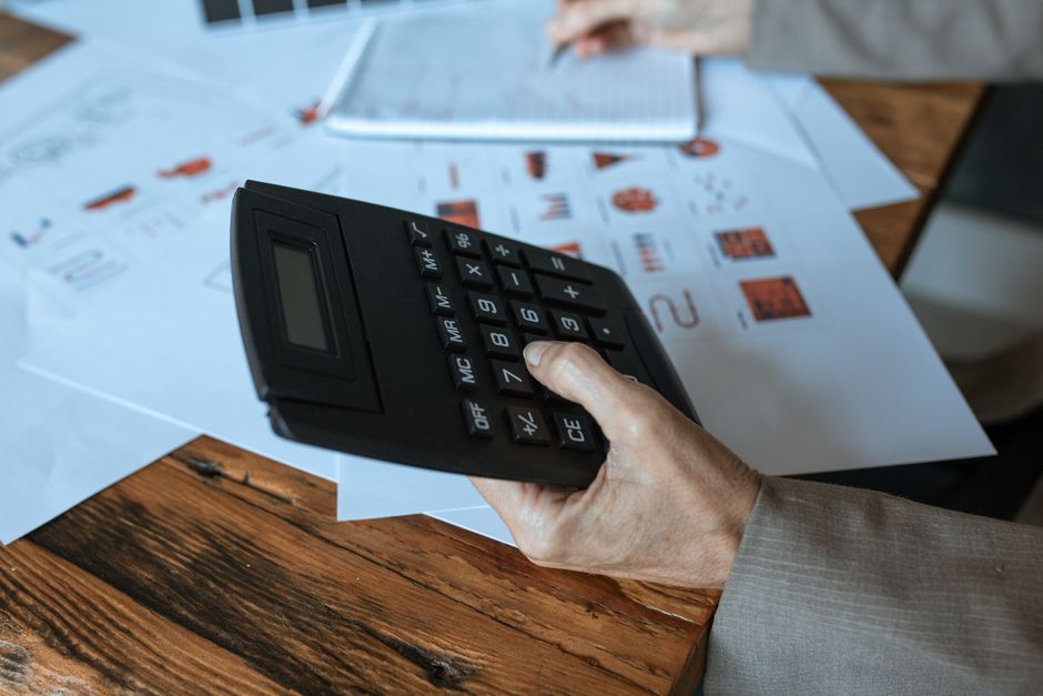 Small business owner using a calculator to plan a realistic sales goal