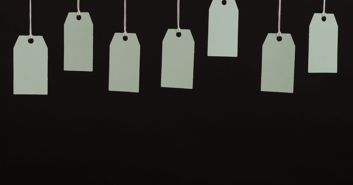 A row of blank paper price tags hanging on white strings against a dark background