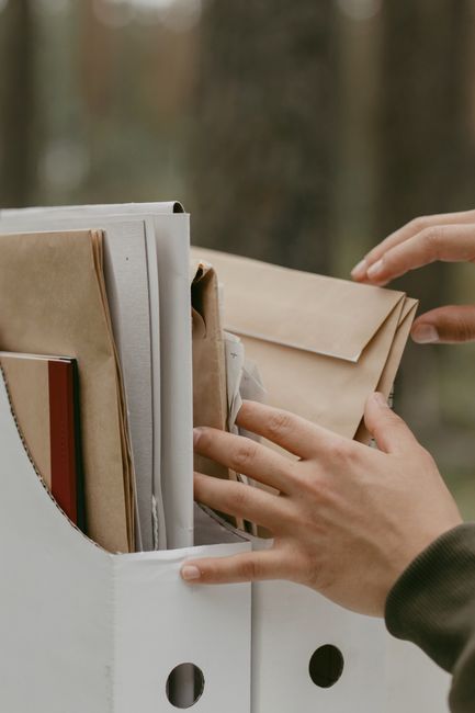 Hands sorting old paperwork into a file box for cleanup