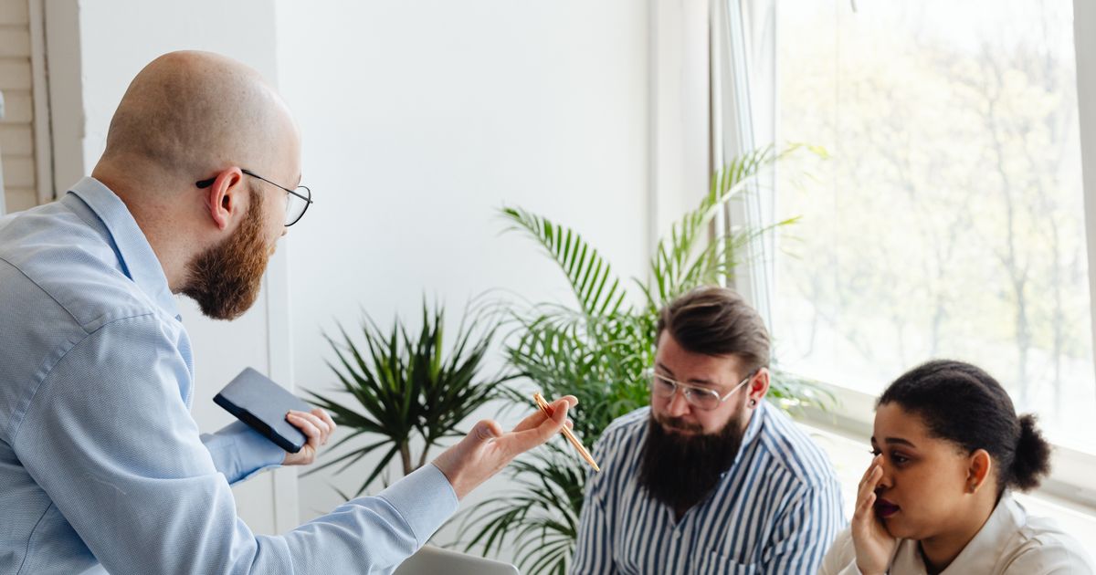 Coworkers in a heated discussion around a desk in a bright office