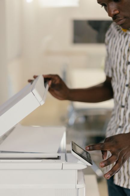 A person operating an office photocopier, making duplicate copies